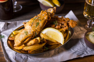 Bananenblüten-BackVisch - veganer Backfisch im Bierteigmantel - als Fisch and Chips auf einem Teller.
