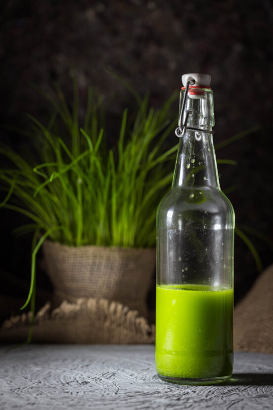 Chive oil in a bottle. Fresh chives behind it.