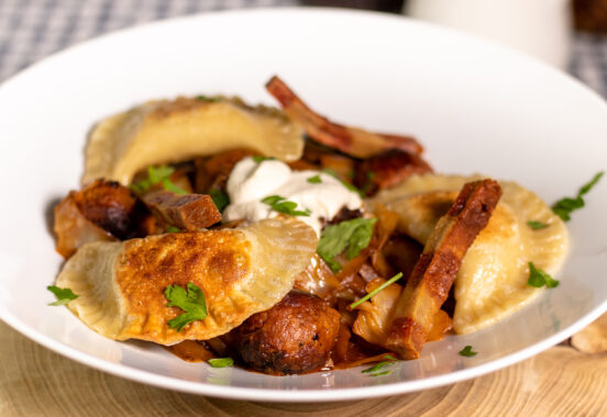 Vegan pierogi with 3 fillings – on a plate with vegan bacon, meatballs and sour cream